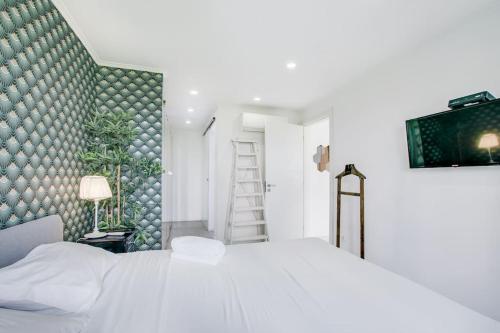 sypialnia z białym łóżkiem i zieloną ścianą w obiekcie White and Light House w Costa de Caparica