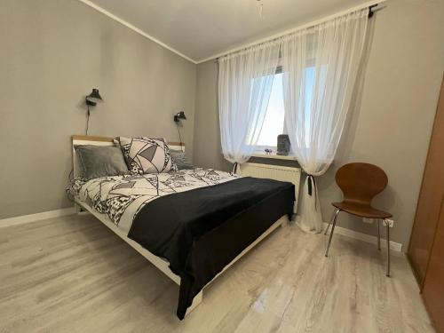 a bedroom with a bed and a window and a chair at Osiedle Leśne 37/28 in Oborniki