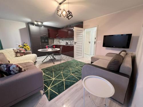 a living room with a couch and a tv and a table at Osiedle Leśne 37/28 in Oborniki