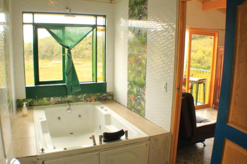 a bath tub in a bathroom with a window at Alegria Hostel Boutique in Guatapé