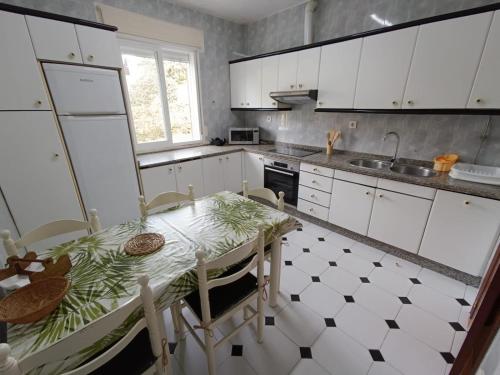 a kitchen with white cabinets and a table with chairs at Fogar de Menduiña in Cangas de Morrazo