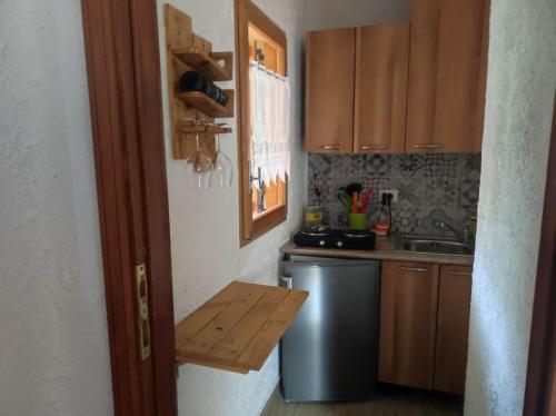 una pequeña cocina con armarios de madera y nevera. en Casa di Viu', en Viù