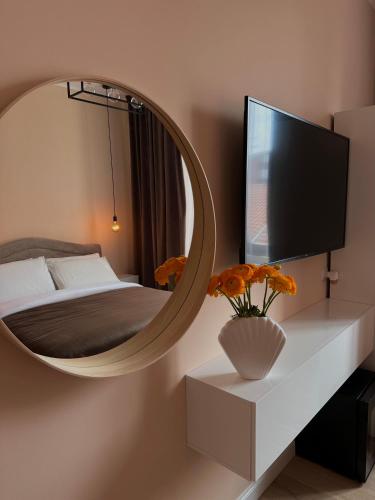 1 dormitorio con espejo, 1 cama y TV en Rhospitality - Visconti Affittacamere, en Rho