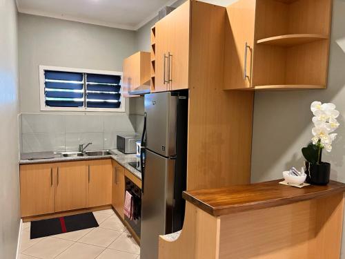 a kitchen with wooden cabinets and a stainless steel refrigerator at Garden Apartments in Nadi