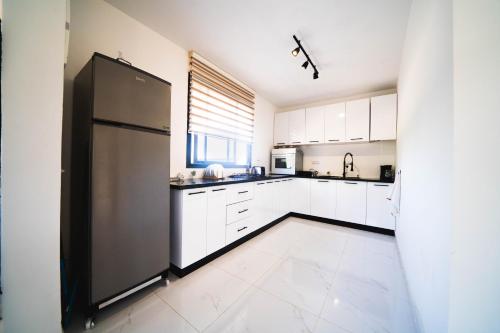 a kitchen with white cabinets and a stainless steel refrigerator at Ferme au cœur la Forêt de Maamoura - Près de Rabat in Rabat