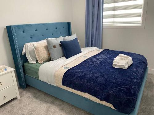 1 cama con cabecero azul y almohadas en un dormitorio en Rewind@Asher - 3 Bed + Den House for Play & Work en Edmonton