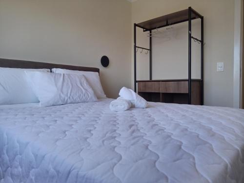 uma grande cama branca num quarto com um espelho em AP Moderno em Pelotas