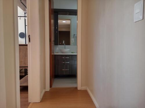 a hallway with a bathroom with a sink and a mirror at AP Moderno in Pelotas