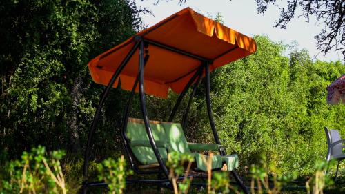 an orange umbrella sitting on a chair in the grass at Ferme au cœur la Forêt de Maamoura - Près de Rabat in Rabat