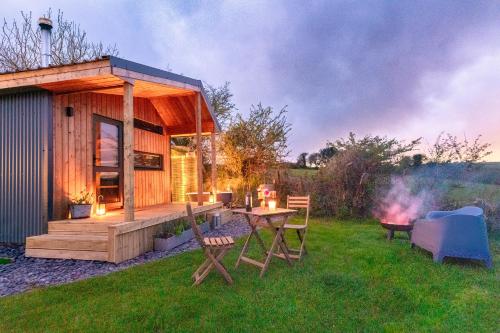a small cabin with a table and chairs in the grass at Luxury Glamping Cabin with Outdoor Bath on Cornish Flower Farm in Truro