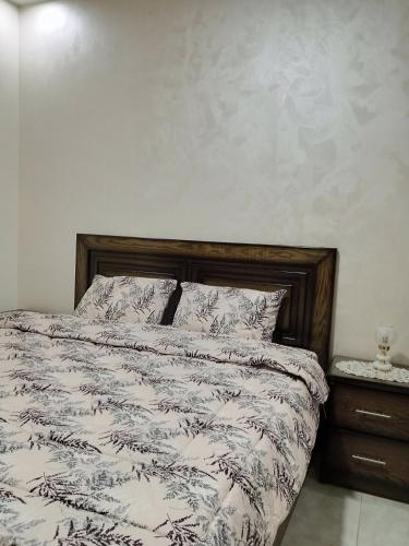 a bed with a black and white comforter and a night stand at Jerash air apartment in Jerash