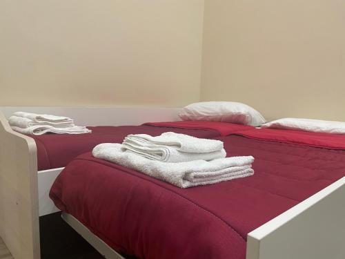 2 Betten mit roter Bettwäsche und weißen Handtüchern darauf in der Unterkunft Nonna Concetta B&B Nocera - Vicino Tribunale di Nocera - Ristrutturato 2022 in Nocera Inferiore