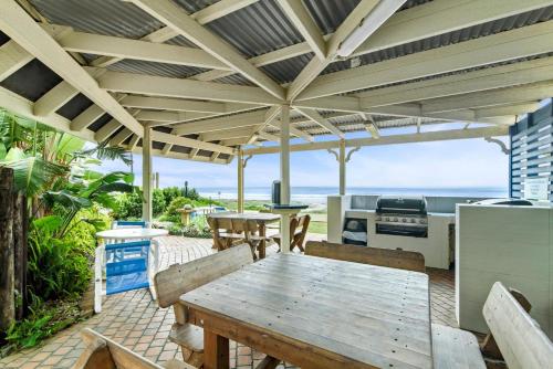 an outdoor patio with a wooden table and a kitchen at Two Bedroom Ocean View Penthouse at Pelican Sands in Gold Coast