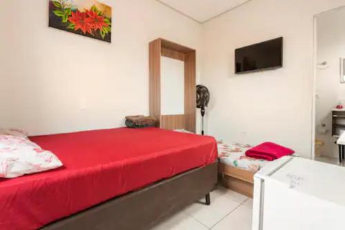 Schlafzimmer mit einem roten Bett und einem TV in der Unterkunft Pousada Casa da Fernanda, Suíte Sky in Praia Grande