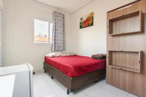 ein Schlafzimmer mit einem roten Bett in einem Zimmer in der Unterkunft Pousada Casa da Fernanda, Suíte Sky in Praia Grande