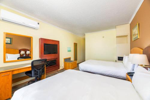 a hotel room with two beds and a desk at Holiday Inn - Bulawayo by IHG in Bulawayo