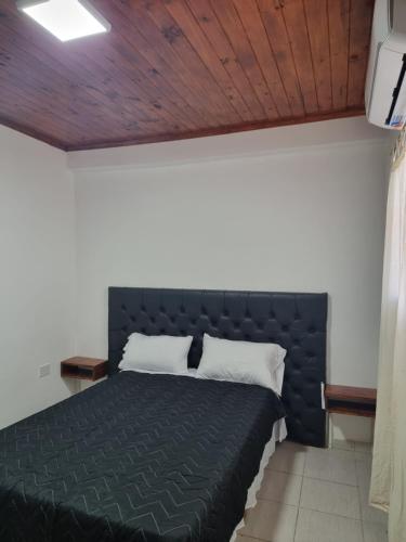 a bedroom with a black bed with a wooden ceiling at Departamento Duvivier II in Resistencia