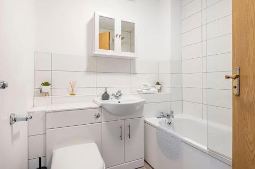 a white bathroom with a sink and a tub and a toilet at Two bedroom flat near Colchester Hospital with free parking and internet in Mile End