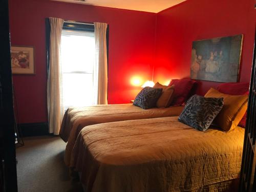 a bedroom with two beds with red walls and a window at Lady Hamilton in Stratford