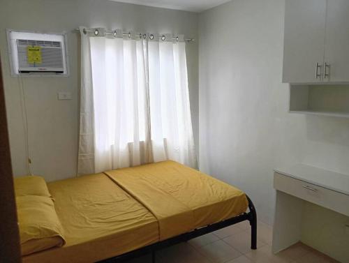 una piccola camera da letto con un letto e una finestra di 2- bedroom condo in Davao a Davao