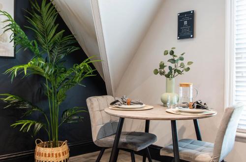 a dining room with a table and two chairs and a plant at The Rampart in Great Yarmouth
