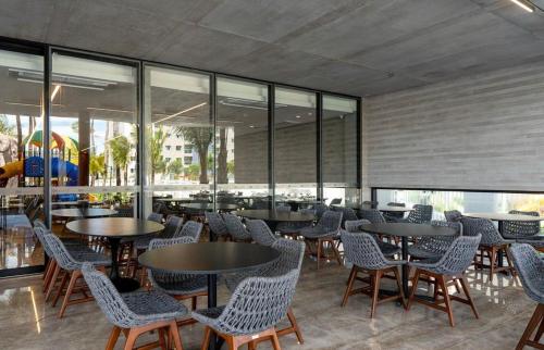 a restaurant with tables and chairs and windows at Salinas Premium Resort in Salinópolis