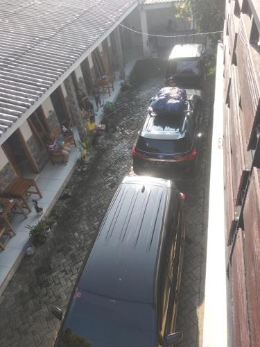 two cars parked in a driveway next to a house at guest house RUMAH KALOKA in Triwung