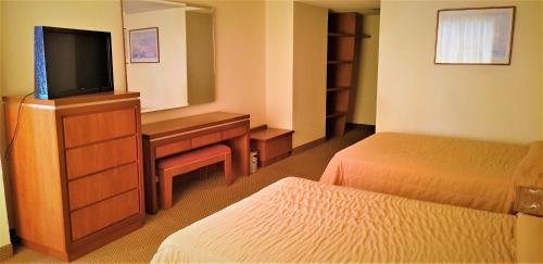 a hotel room with two beds and a flat screen tv at Hotel Finisterre in Mexico City
