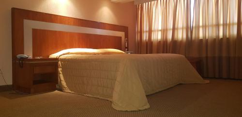 a bedroom with a bed with a wooden head board at Hotel Finisterre in Mexico City