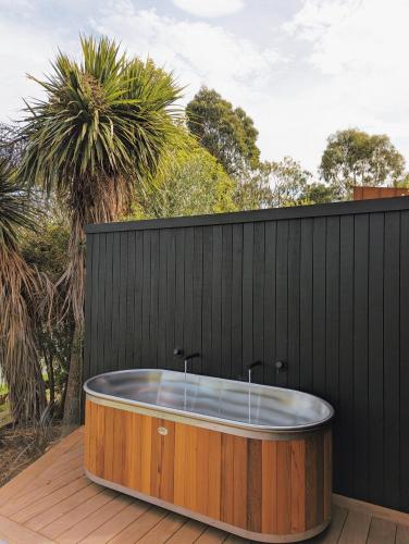 a bath tub on a deck with a black fence at Tussock Hill Vineyard Retreats in Christchurch