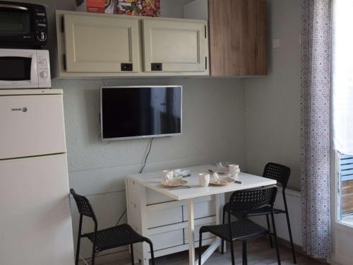 une petite cuisine avec une table et des chaises blanches dans l'établissement Charmante Maisonnette avec Piscine, Terrasse et Parking à 250m de la Plage à Marseillan - FR-1-387-195, à Marseillan