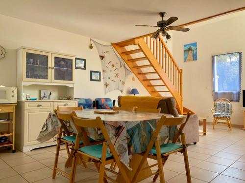 une cuisine avec une table et des chaises ainsi qu'un escalier dans l'établissement Pavillon à Longeville-sur-Mer, proche plage, 6 pers, 3 ch, terrasse, parking privé - FR-1-336-135, à Longeville-sur-Mer