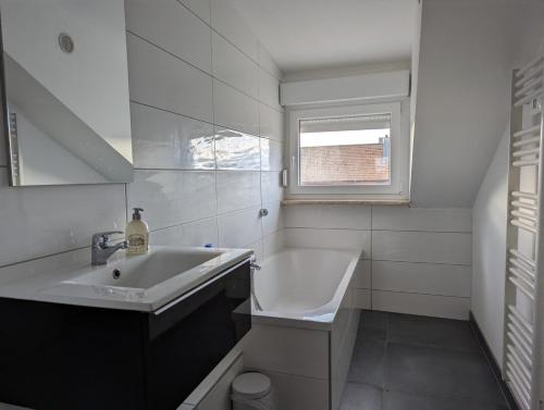 ein weißes Bad mit einem Waschbecken und einem Fenster in der Unterkunft Le Vauban - appartement 2 chambres, salon, cuisine équipée, parking et wifi gratuit in Mulhouse