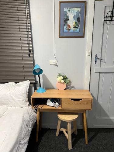 a desk in a bedroom with a bed and a desk with a lamp at A lovely studio in Kings Meadows in Kings Meadows