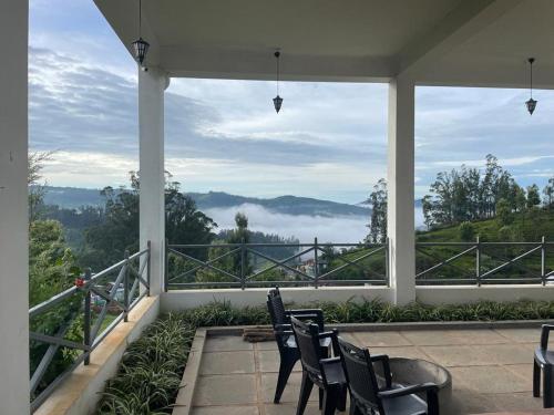 a porch with chairs and a view of the mountains at Orchard Valley View in Ooty