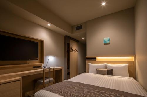 a bedroom with a bed and a flat screen tv at HOTEL OLE INN in Shizuoka