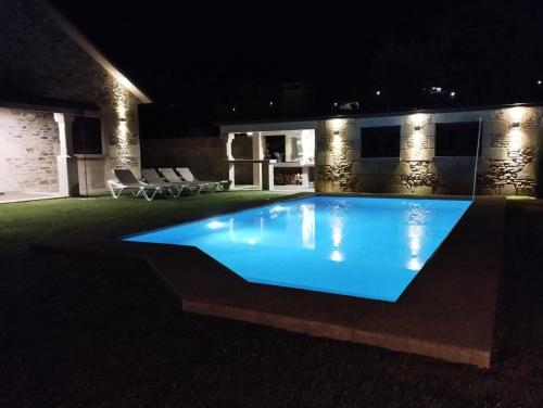 uma piscina iluminada à noite em VILLA A CANLE em Catoira
