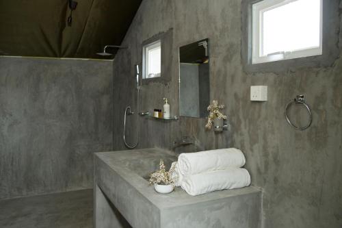 a bathroom with a sink and a shower with towels at Yala Wild Hut - Yala in Tissamaharama