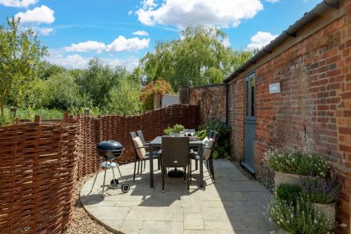 a patio with a barbecue grill and a brick wall at The Granary in Tunstead