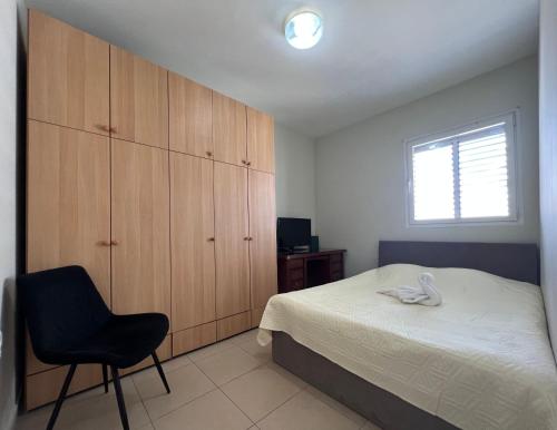 1 dormitorio con 1 cama, 1 silla y 1 ventana en ISRALUX APARTMENTS, en Bat Yam