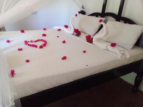 a bed with pink flowers on it at The Dream Garden Bungalow in Kizimkazi