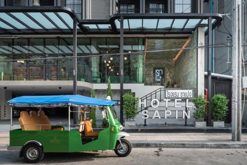 a green golf cart parked in front of a building at Hotel Sapin in Pom Prap