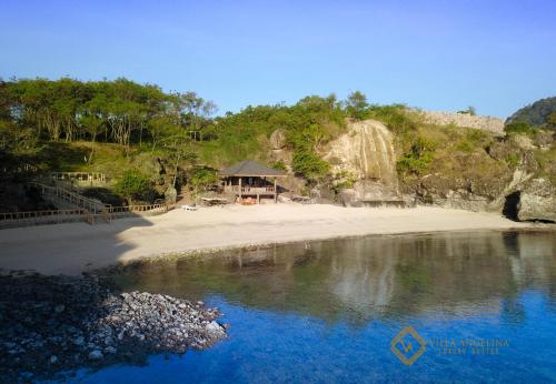 a beach with a house on the sand and water at Villa Angelina Luxury Suites in Dapitan