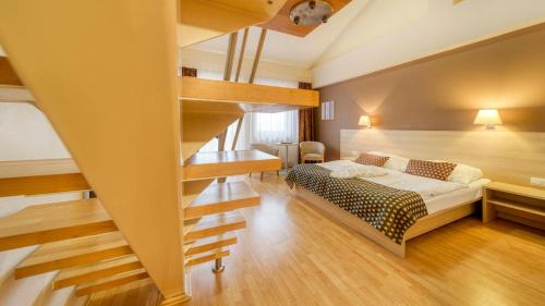 a bedroom with a bed and a spiral staircase at Wellness Hotel Patince in Patince