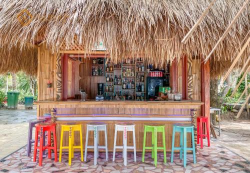 un bar avec des tabourets colorés devant une cabane dans l'établissement Villa Angelina Luxury Suites, à Dapitan