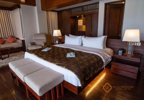 a hotel room with a large bed and a chair at Villa Angelina Luxury Suites in Dapitan