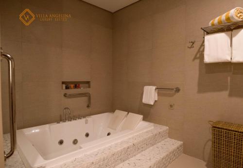 a white bath tub in a bathroom with towels at Villa Angelina Luxury Suites in Dapitan