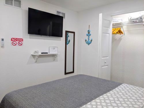 1 dormitorio con 1 cama y TV de pantalla plana en la pared en Sea Breezes Holiday, A Charming Suite Near The Beaches, en Holiday