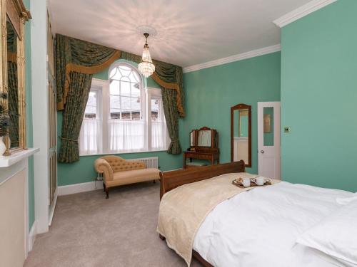 um quarto com paredes azuis, uma cama e uma janela em The Counting House em Wirksworth
