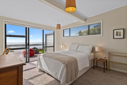 ein Schlafzimmer mit einem Bett mit Blick auf das Meer in der Unterkunft Blue Skies Sunrise - Mangawhai Heads Holiday Home in Mangawhai